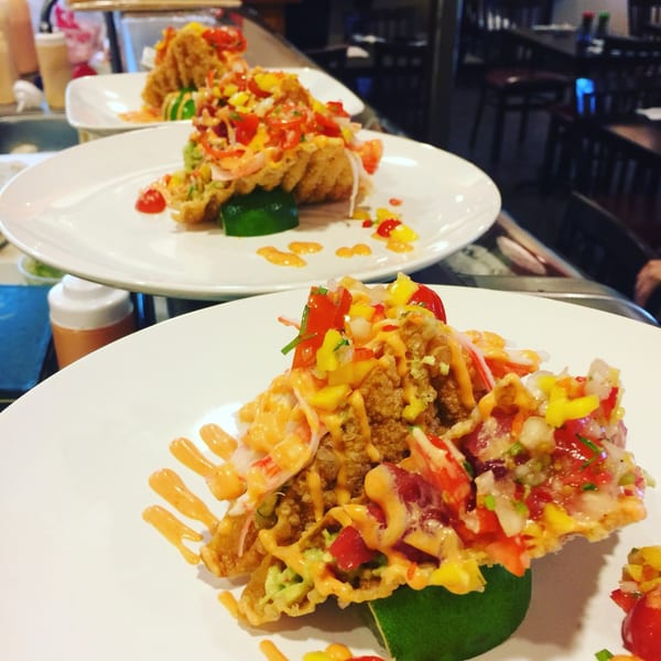 Three plates of Fusion Tea Lounge's crispy tacos with colorful toppings and sauce, ready to be served.