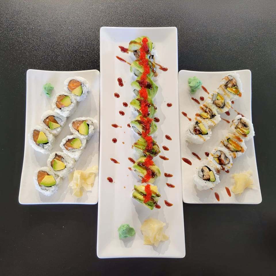 Three plates of sushi rolls, including salmon avocado, dragon, and eel rolls, with wasabi and ginger.