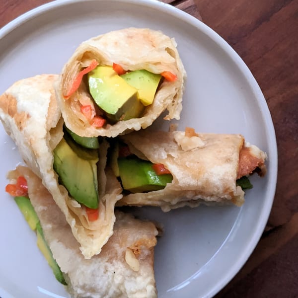 Several Fusion Tea Lounge wraps with avocado and red peppers on a white plate.